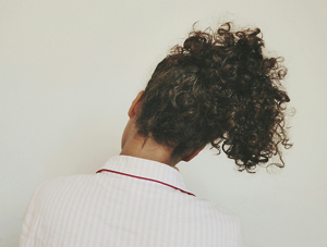 Back view of a young woman with tied-up dark brown curly hair